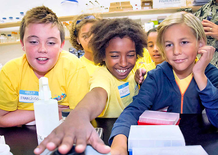 students smiling and engaging in experiments