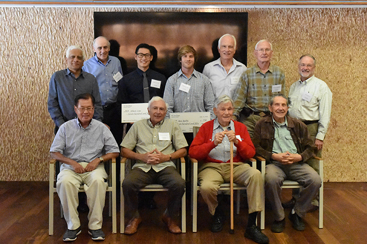 11 men standing with 2 holding checks