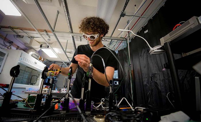 A man wears goggles as he works on an experiment.