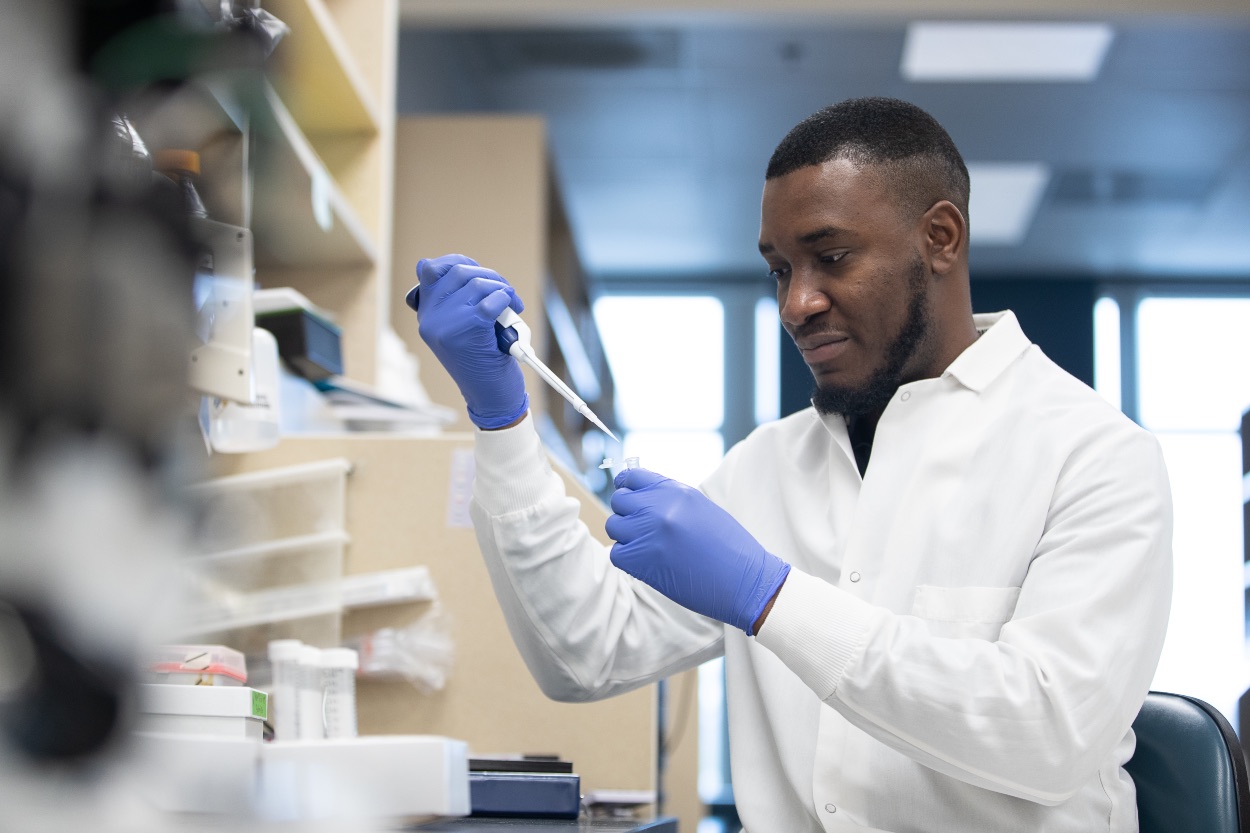 Scientist measuring liquid in pipette 